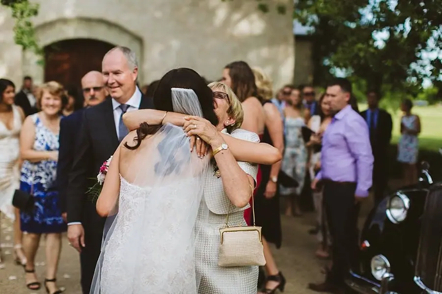 Bride embracing a woman in glasses outside the chapel.