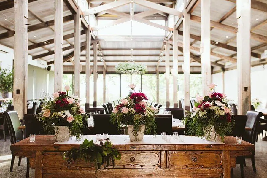 Pink floral arrangements on a rustic wooden dresser in the bright reception room.