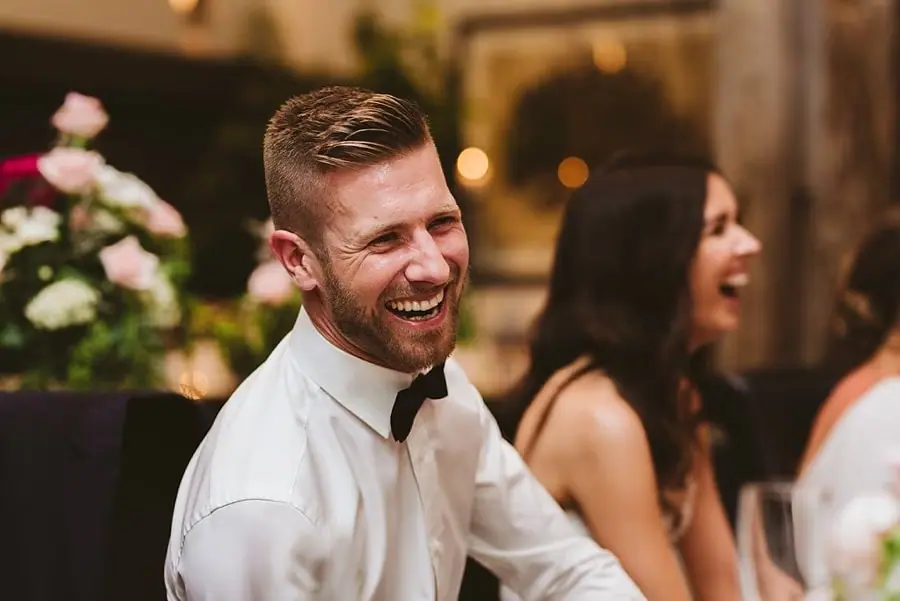 Groom laughing beside the bride at the evening reception.