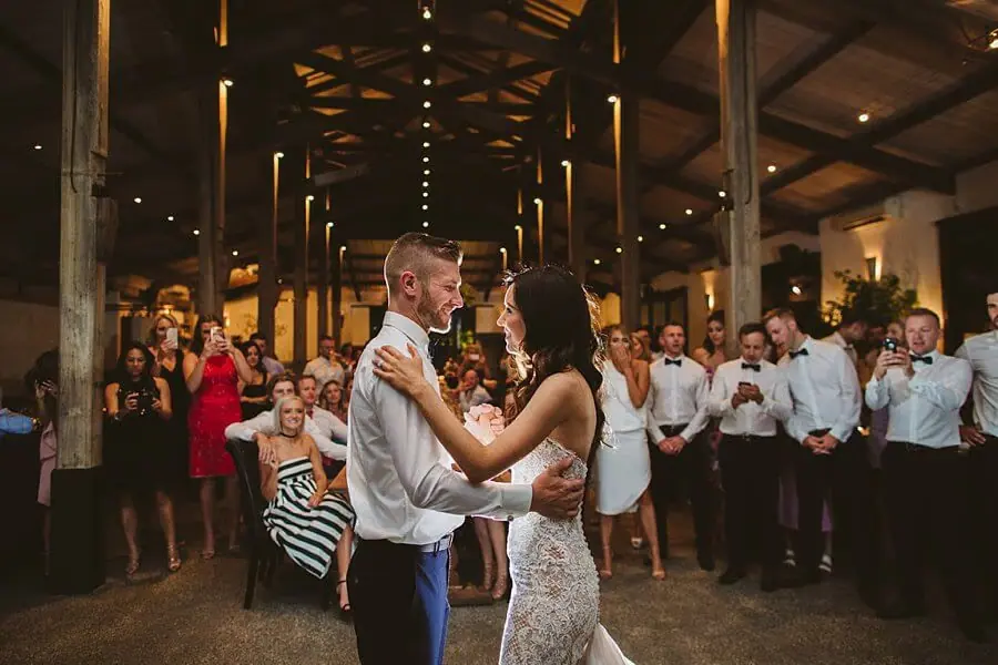 Bride and groom dancing together while guests watch around the floor.
