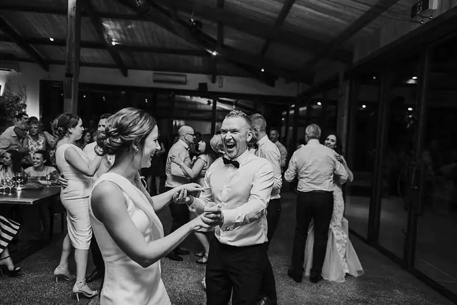 Black-and-white photograph of guests laughing and dancing with partners.