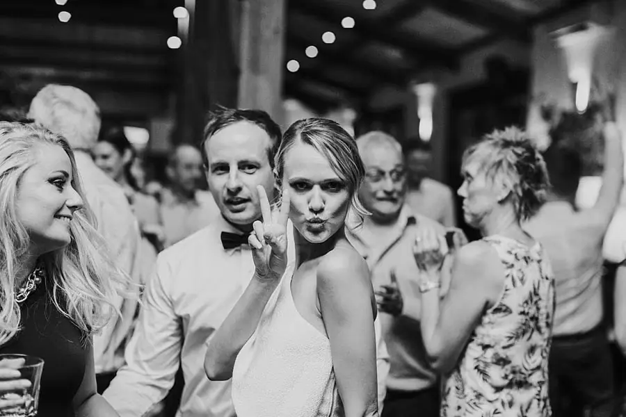Black-and-white photograph of a woman making a playful pose beside a man on the dance floor.