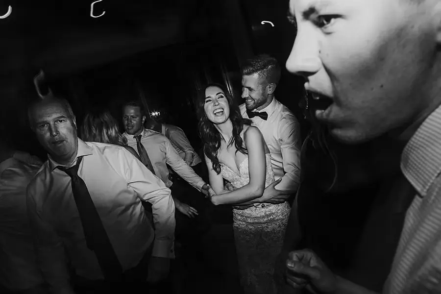 Black-and-white photograph of the bride laughing with guests on the dance floor.