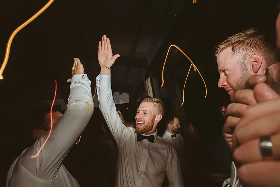Two men high-fiving among guests on the dance floor.