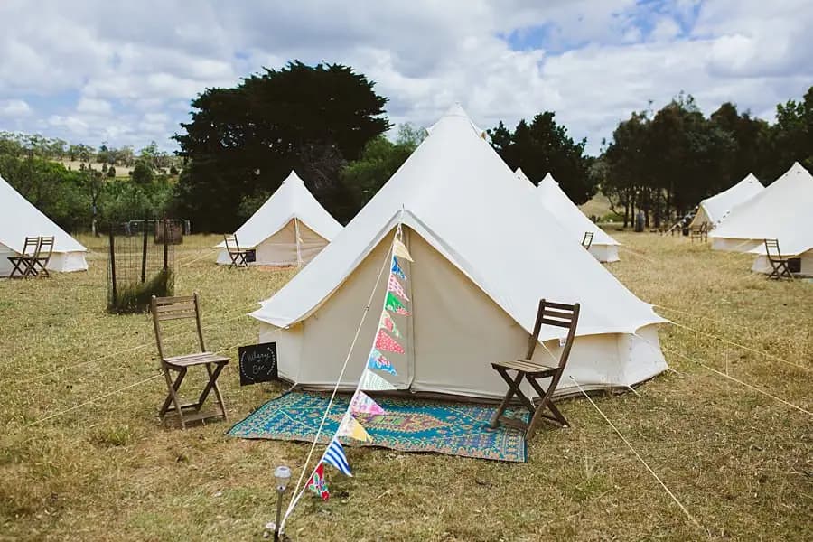 White bell tent with bunting and folding chairs in a grassy campsite