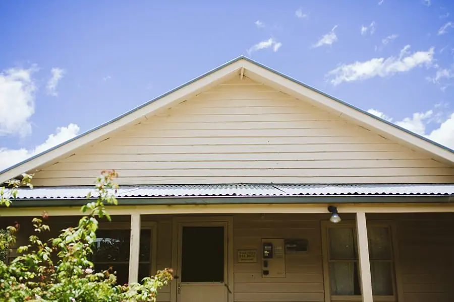 Weatherboard house and covered verandah beneath a blue sky