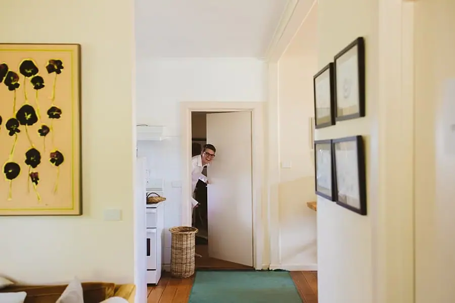 Man peering through an open doorway in a bright house