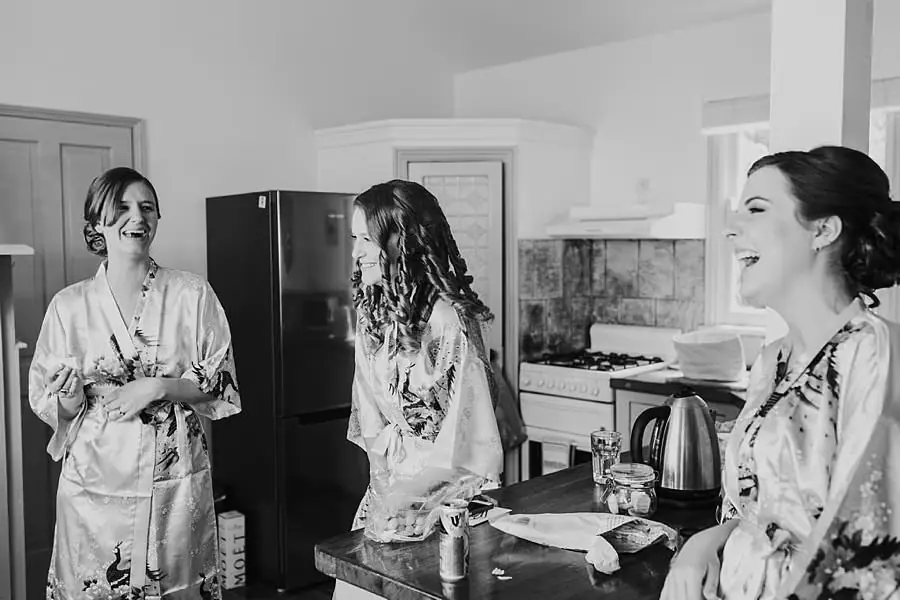 Black-and-white photograph of three women laughing together in patterned robes