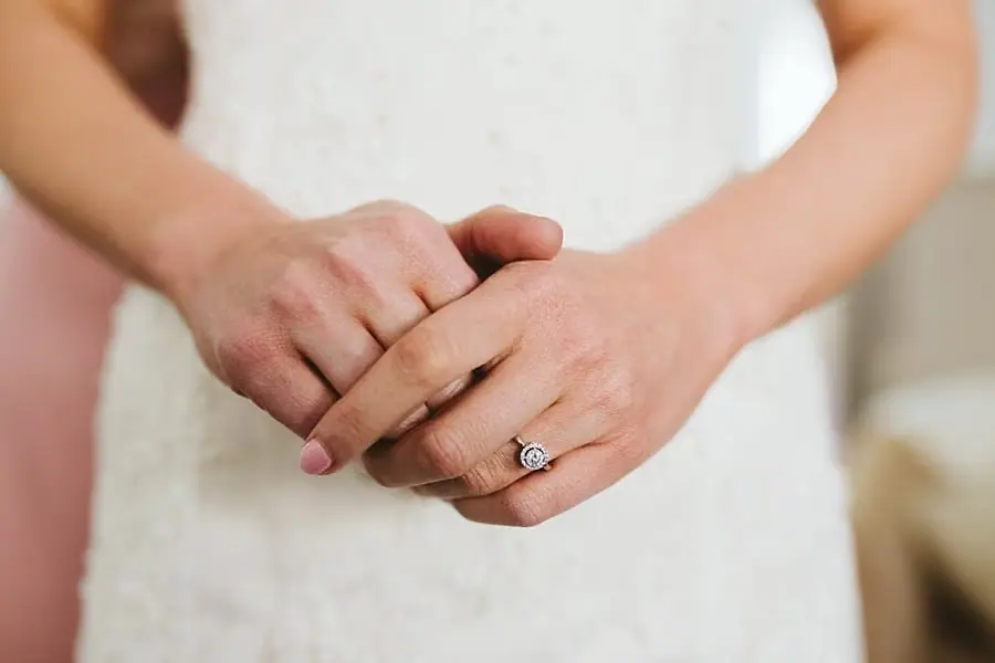 Close view of the bride's hands and ring against her white dress