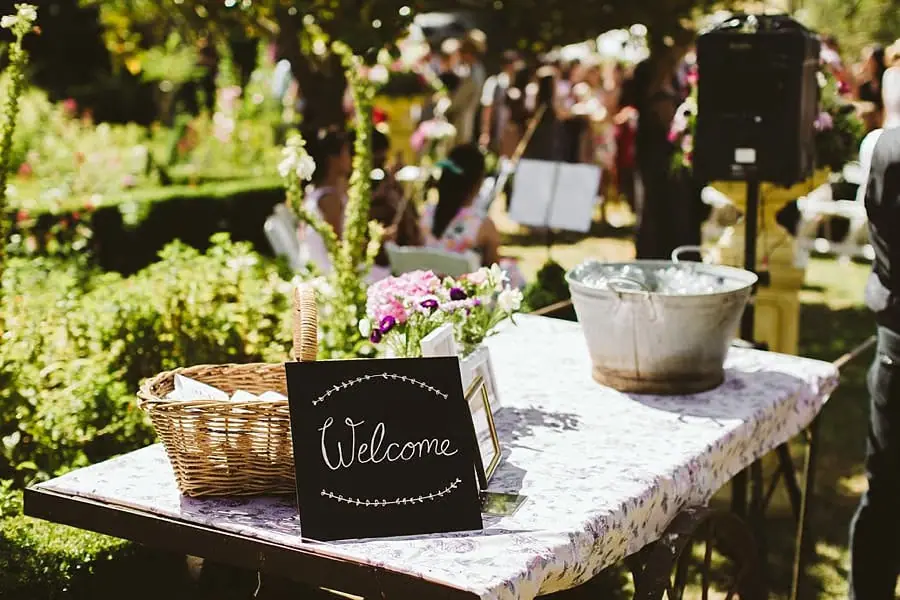 Wedding welcome table with flowers, a basket and a metal drinks bucket