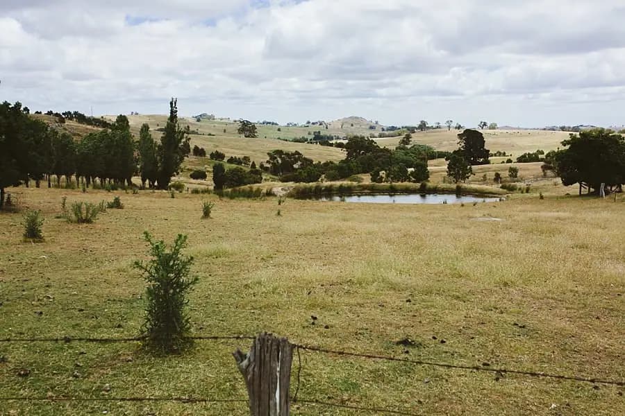 Rolling farmland and a pond beneath a cloud-filled sky