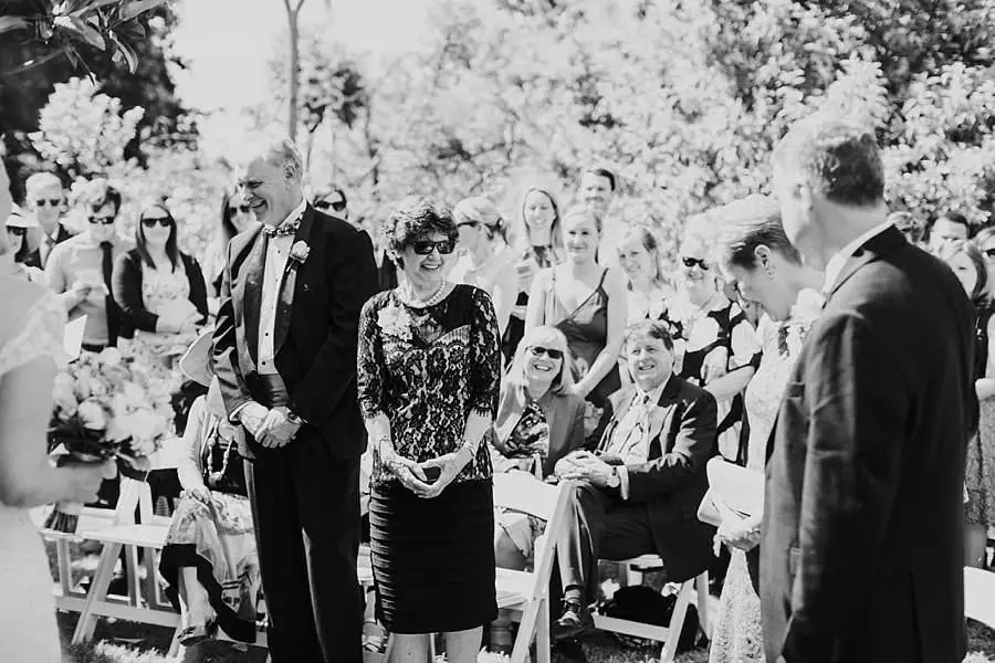 Black-and-white photograph of standing guests watching the garden ceremony