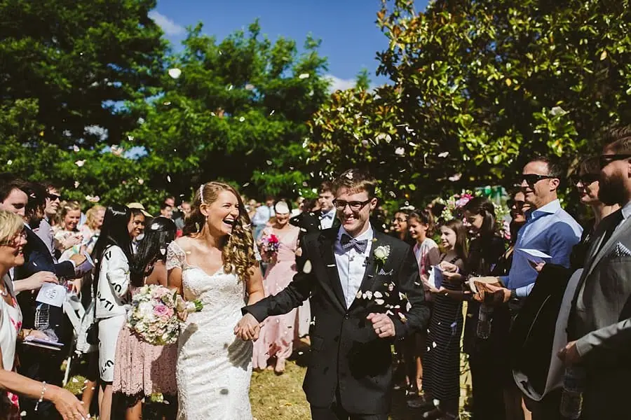 Bride and groom walking between guests tossing pale petals