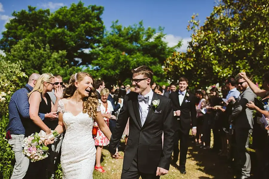 Bride and groom laughing together while walking past cheering guests