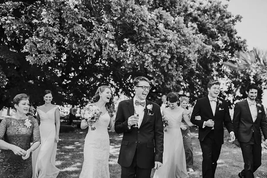 Black-and-white photograph of the wedding party walking through the garden with drinks