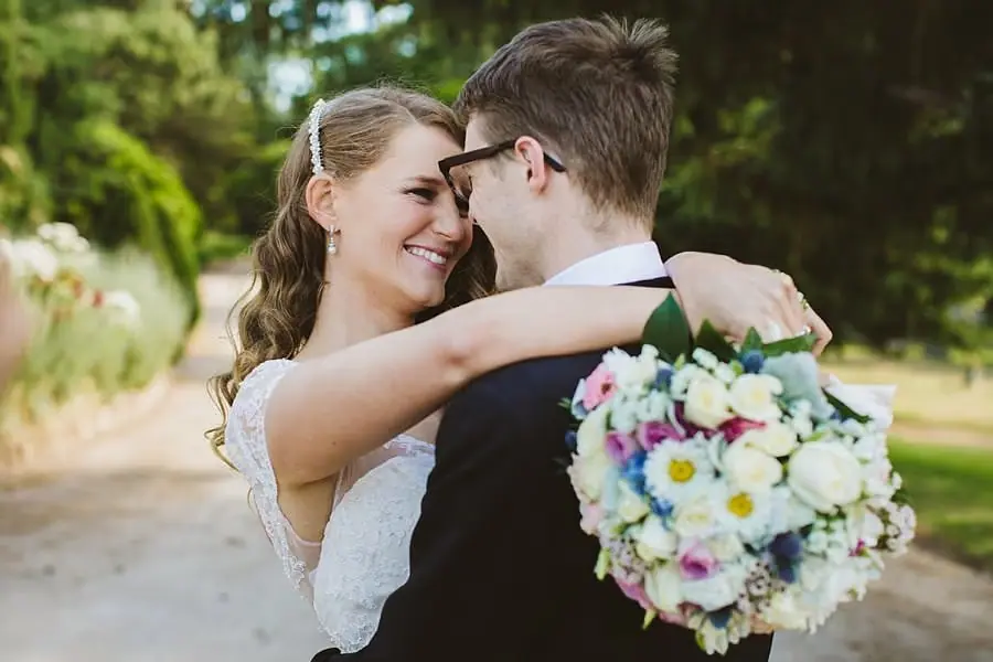 Bride smiling closely at the groom with her bouquet resting over his shoulder