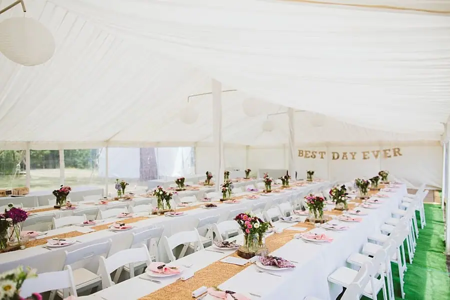 Long decorated tables and white chairs beneath a white marquee ceiling