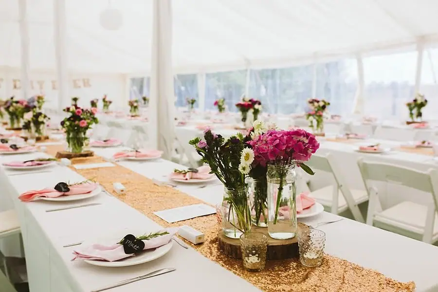 Flower-filled jars and a gold runner decorating a reception table