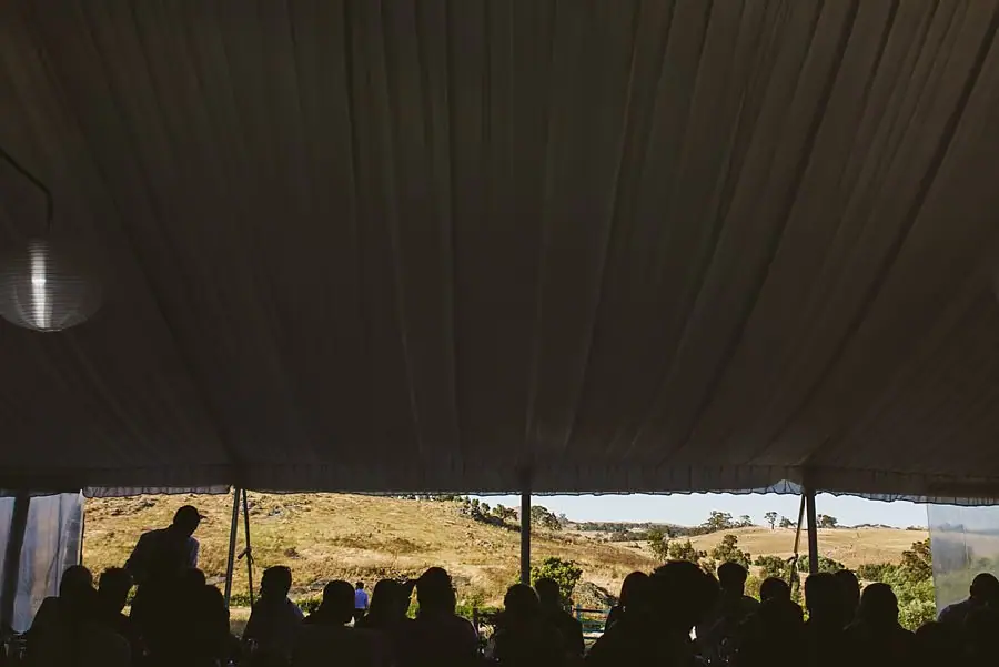 Silhouetted guests inside the marquee with countryside visible beyond