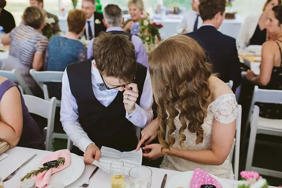 Bride and groom leaning together to look at papers at their reception table