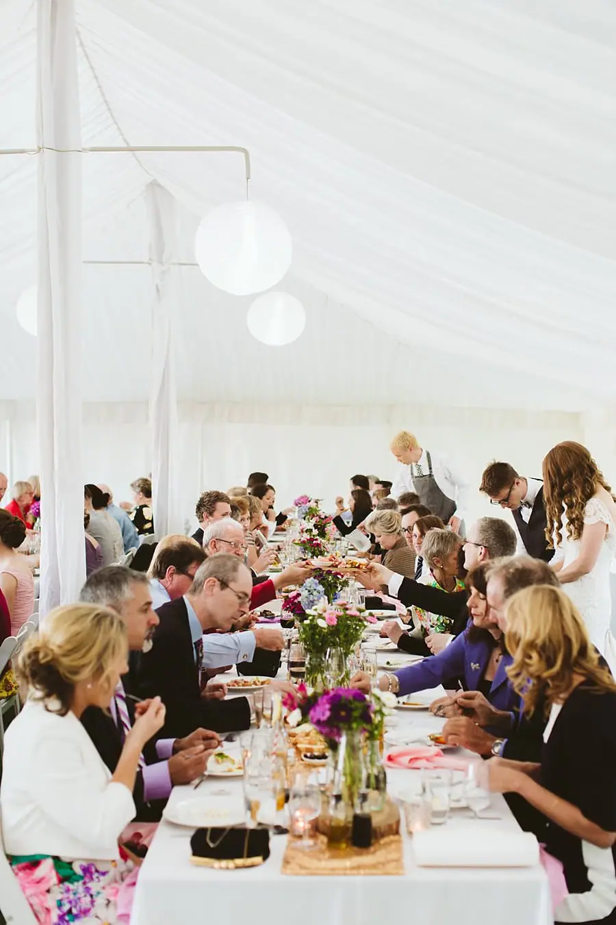 Wedding guests seated along flower-decorated reception tables
