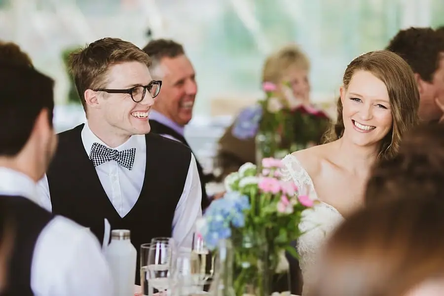 Bride and groom smiling together at their reception table