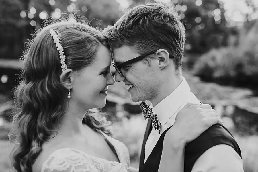 Black-and-white close portrait of the bride and groom touching foreheads