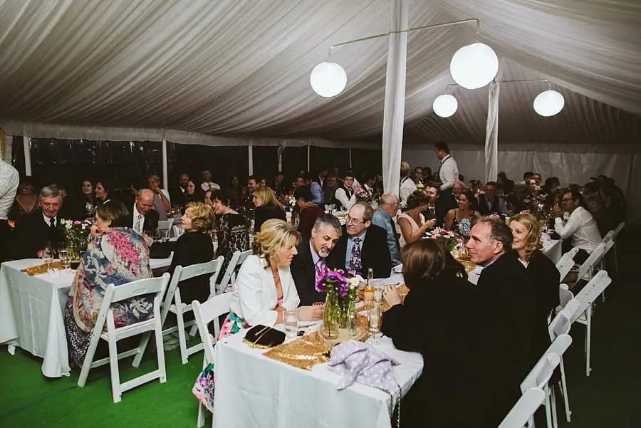 Guests dining beneath glowing round lanterns inside the marquee