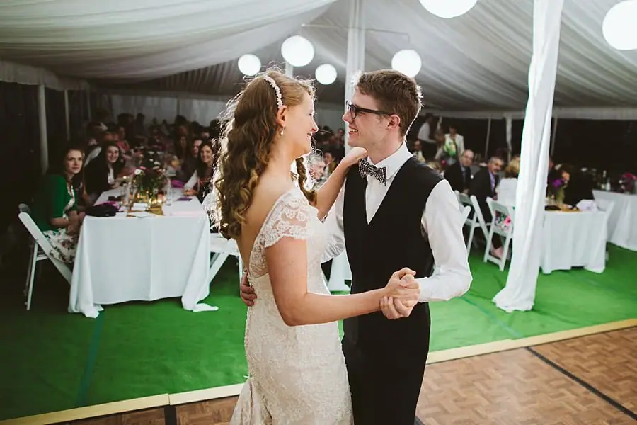 Bride and groom holding hands on the dance floor while guests watch