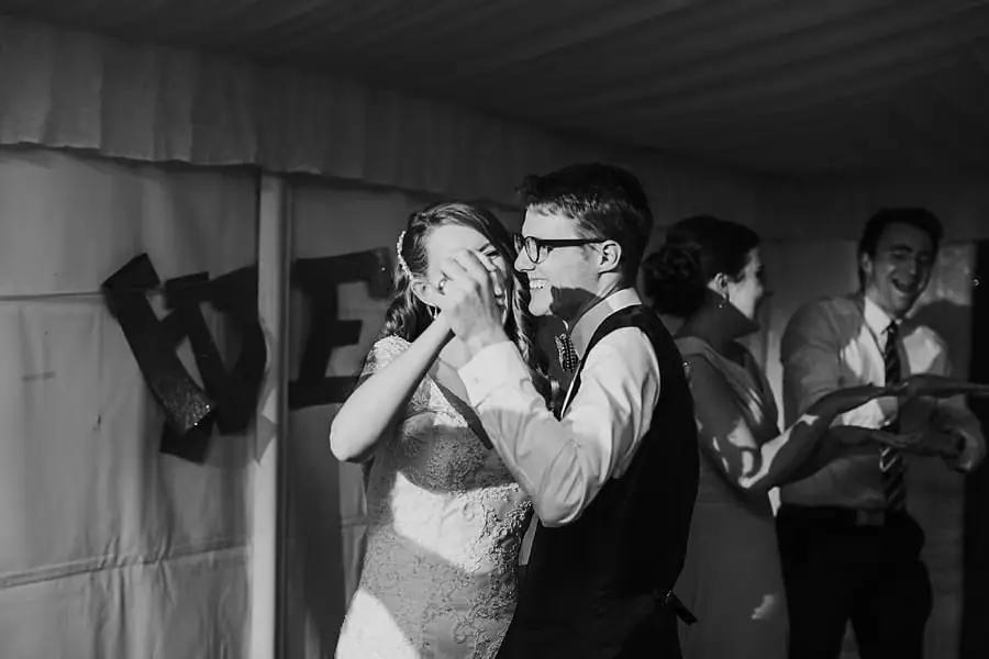 Black-and-white photograph of the bride and groom dancing among guests