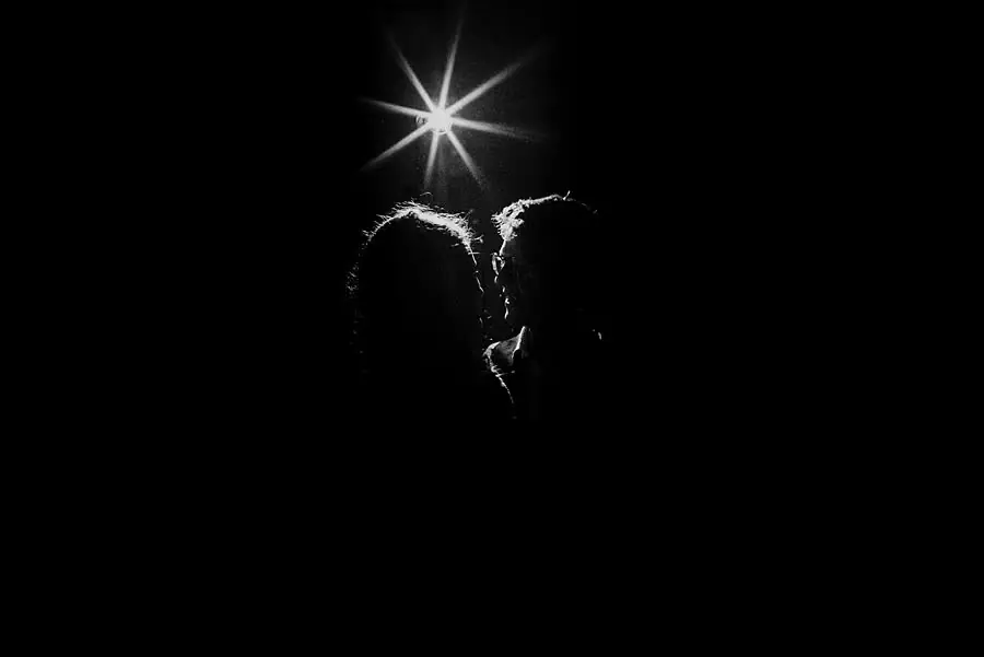 Black-and-white silhouette of the bride and groom beneath a bright starburst light