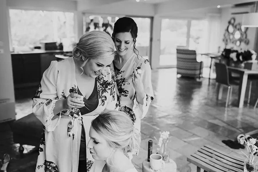 Black-and-white photograph of women in floral robes helping one another get ready.