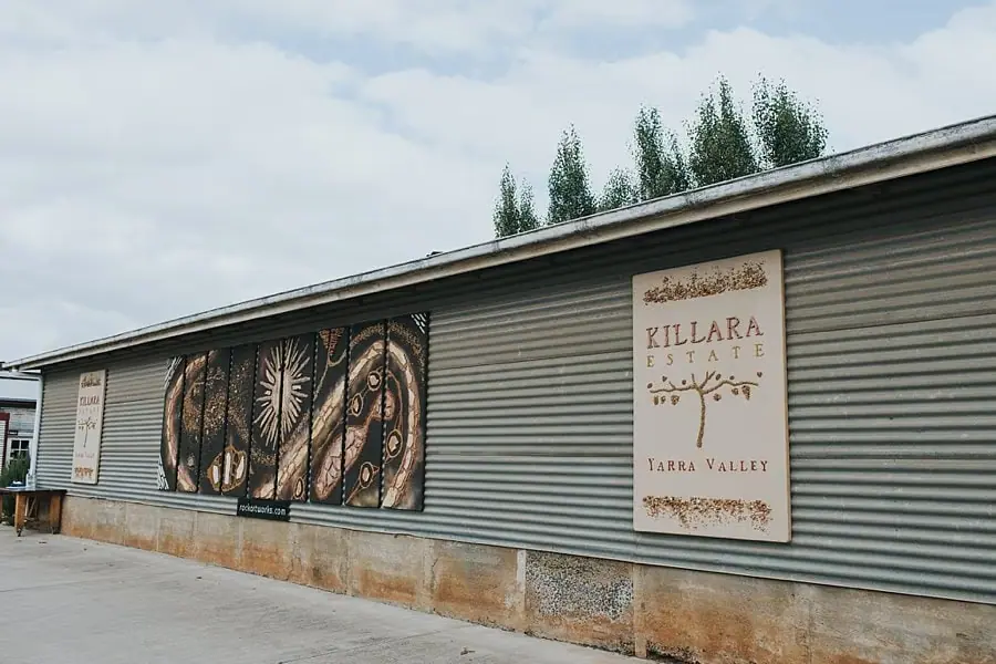 Corrugated winery building with decorative artwork and a venue sign.