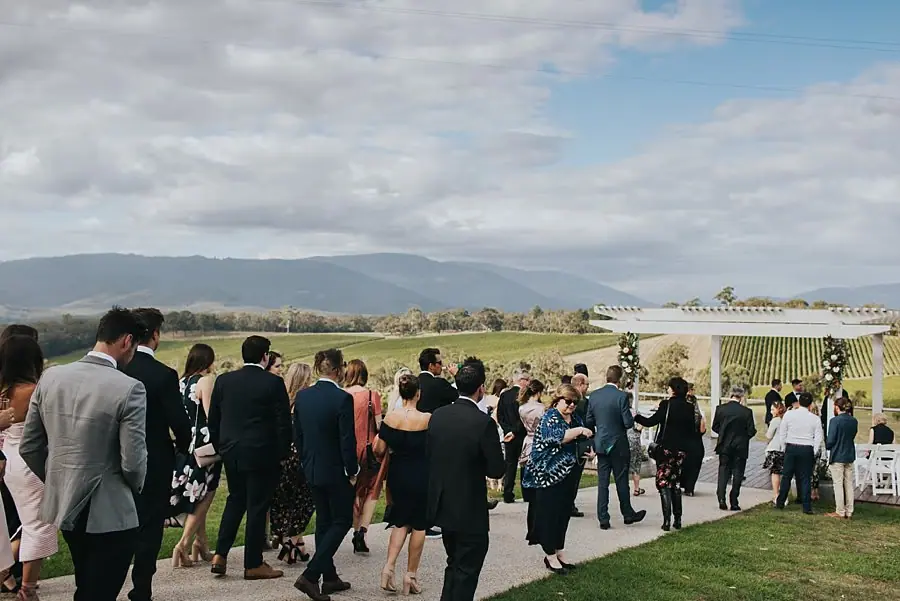 Guests walking toward the outdoor ceremony pergola beneath mountain views.