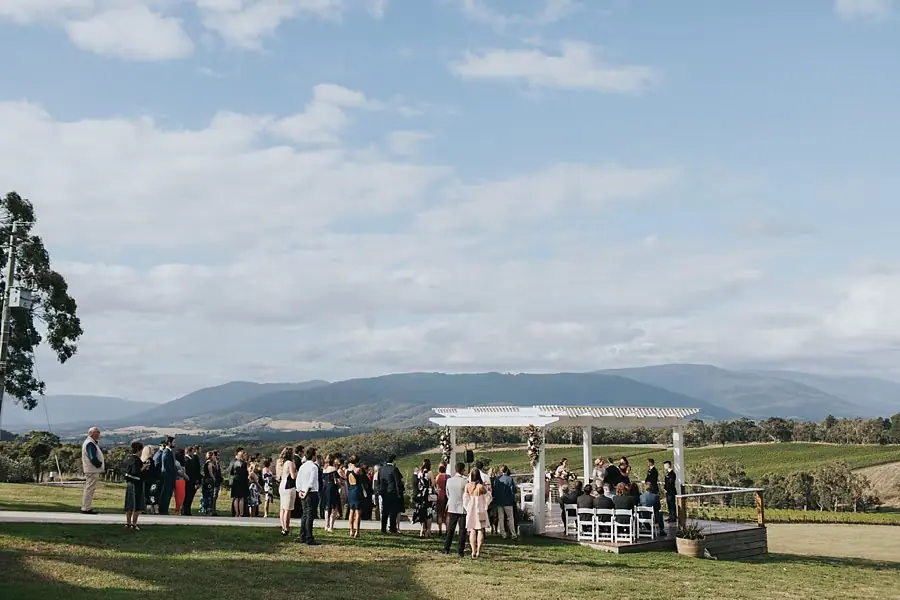 Wide view of guests gathered around the outdoor ceremony overlooking mountains.