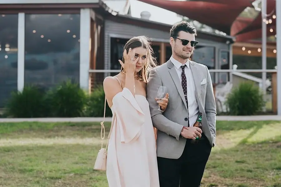 Woman touching her eye while standing beside a man in a grey jacket.