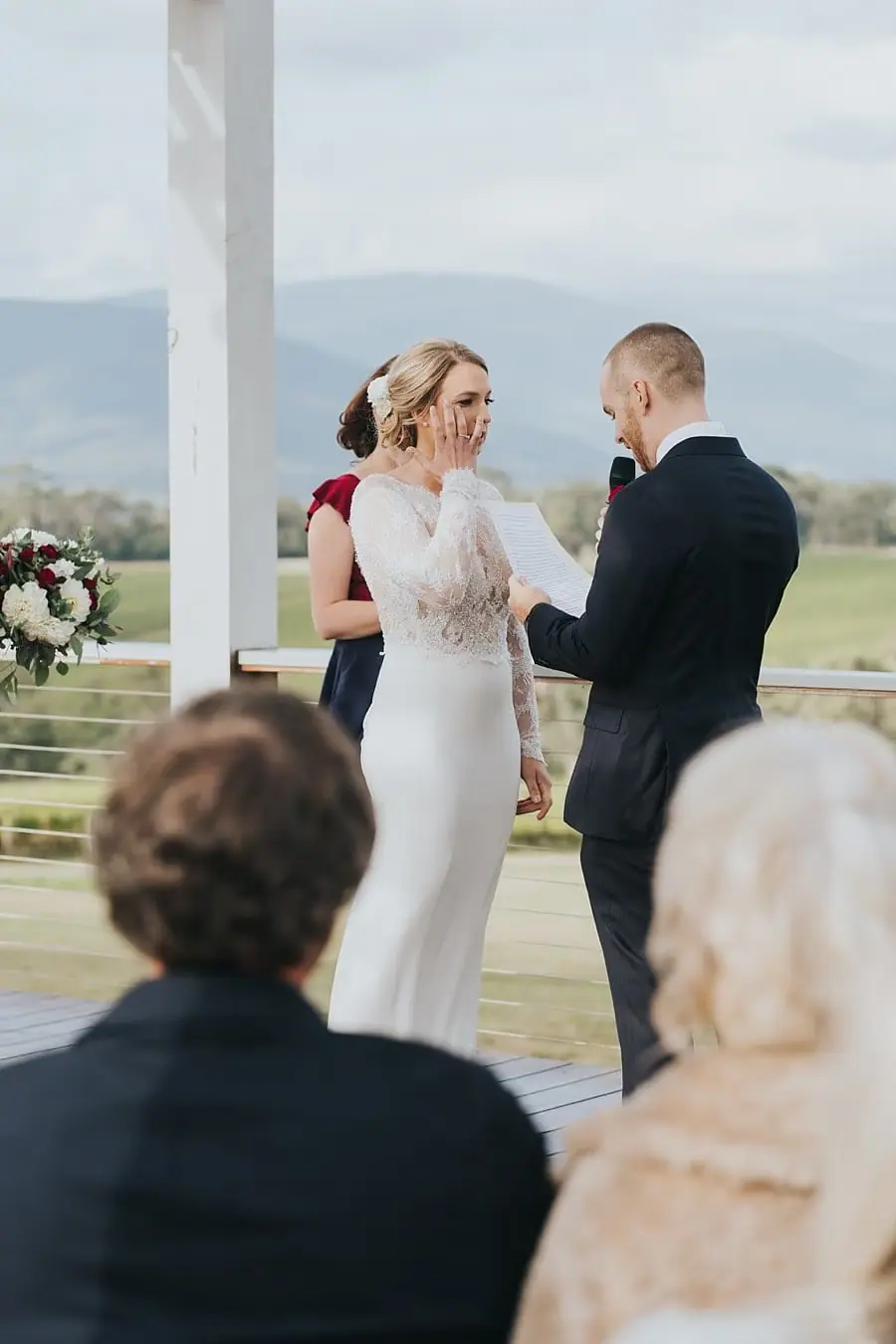 Bride and groom exchanging vows under the white ceremony pergola.