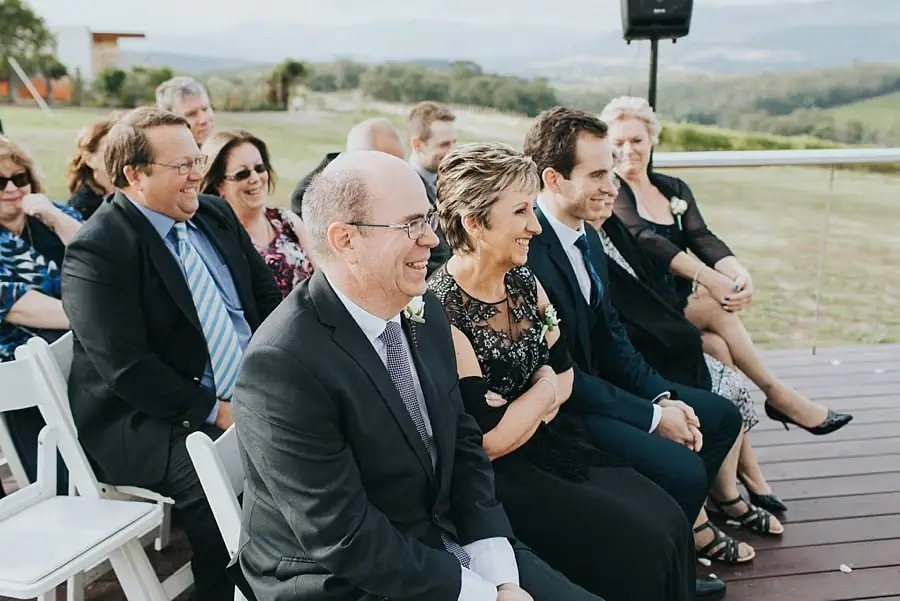 Guests smiling from rows of white ceremony chairs.