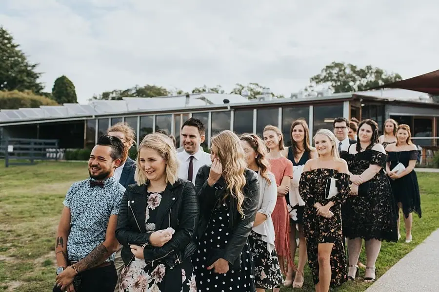 Standing guests watching the couple outside the reception building.