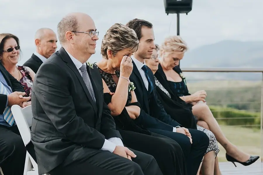 Seated guests reacting to the ceremony, including a woman touching her face.