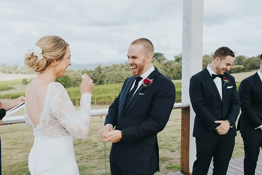 Groom laughing while the bride lifts a hand during the ceremony.