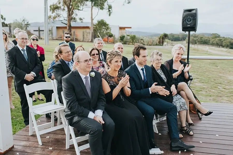 Guests clapping and smiling beside the vineyard ceremony.