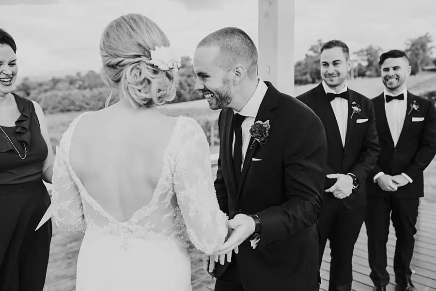 Black-and-white photograph of the couple holding hands and laughing together.