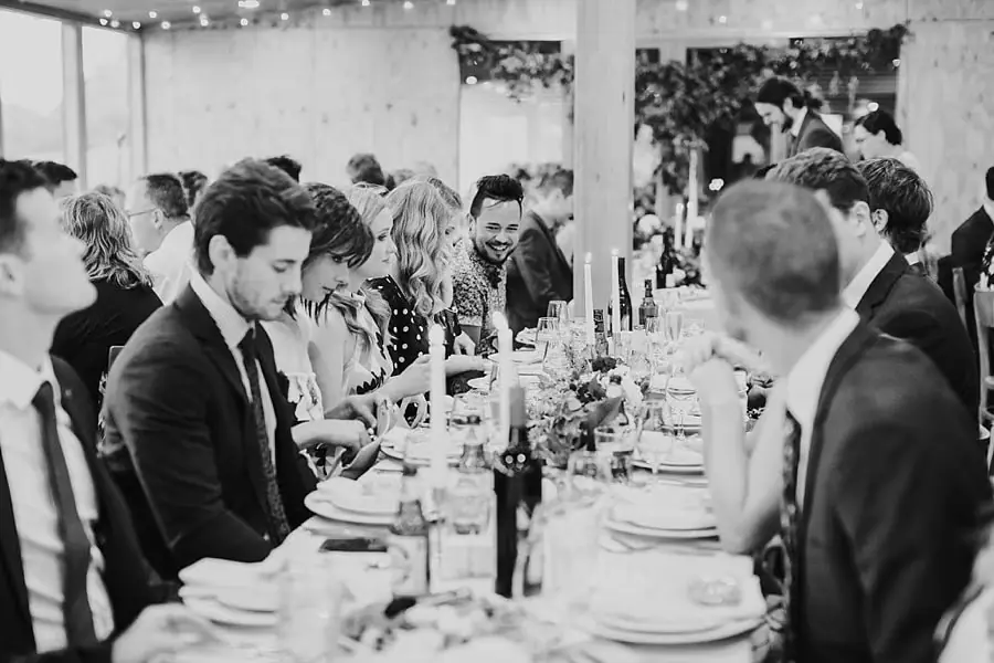 Black-and-white photograph of guests seated along a reception table.