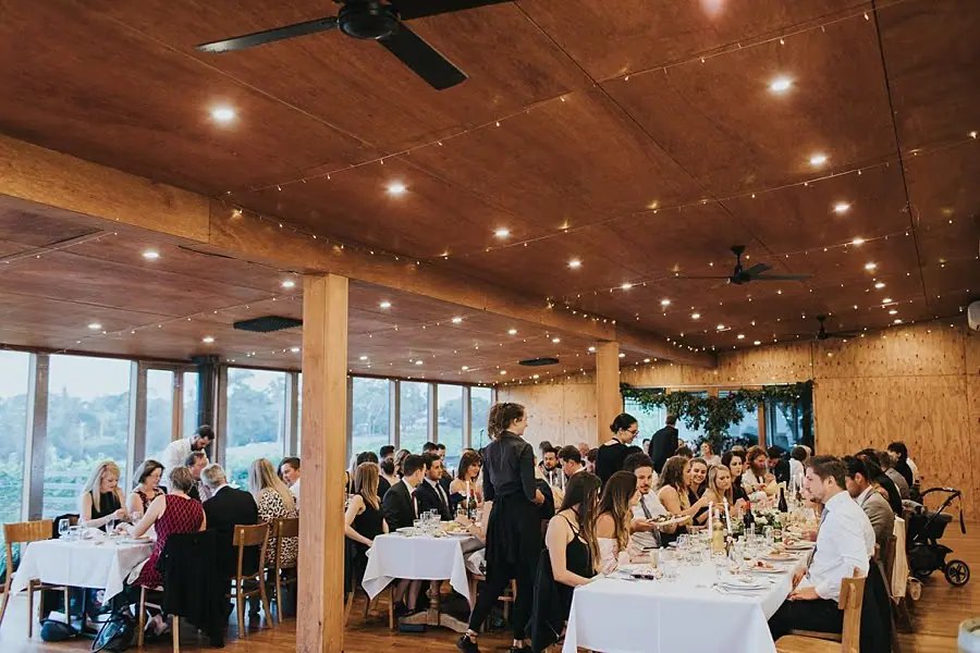 Guests dining beneath small lights in the timber-lined reception room.