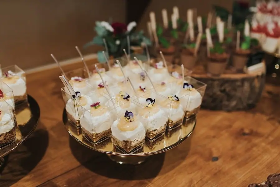 Small layered desserts in clear glasses arranged on a gold stand.