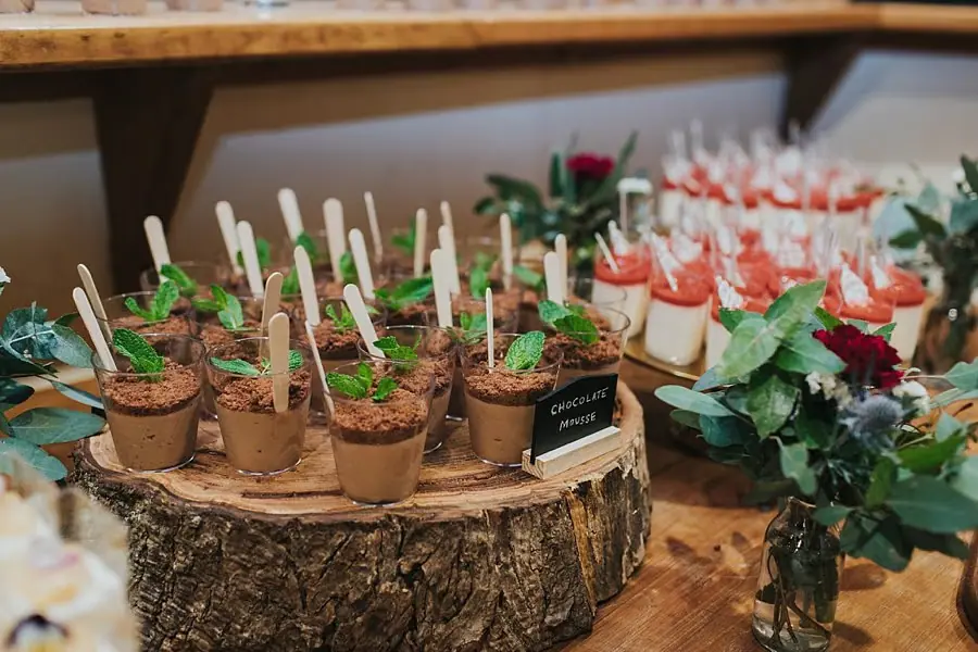 Chocolate dessert cups with spoons arranged on a wooden slab.