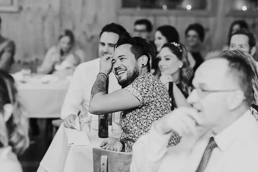 Black-and-white photograph of guests laughing at a reception table.