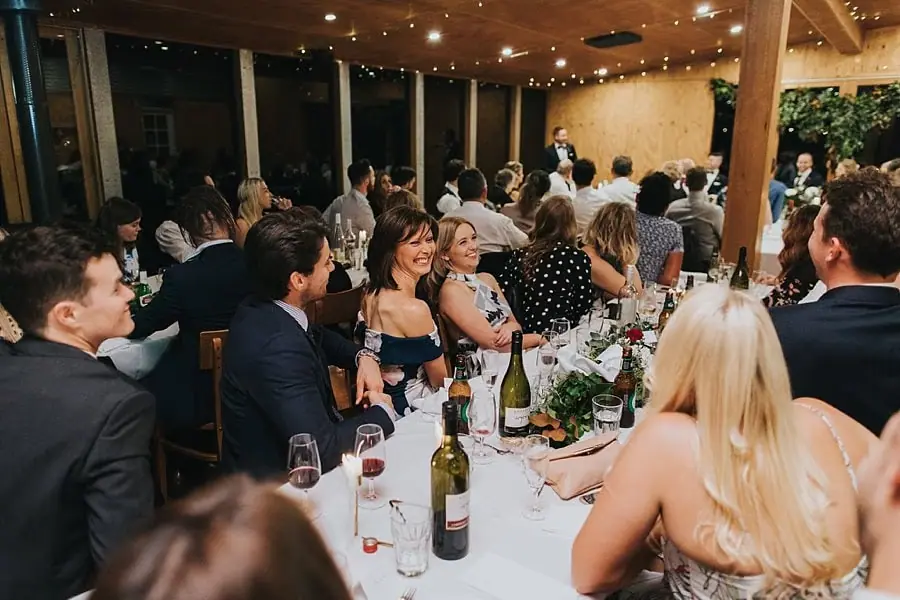 Guests watching speeches beneath strings of reception lights.