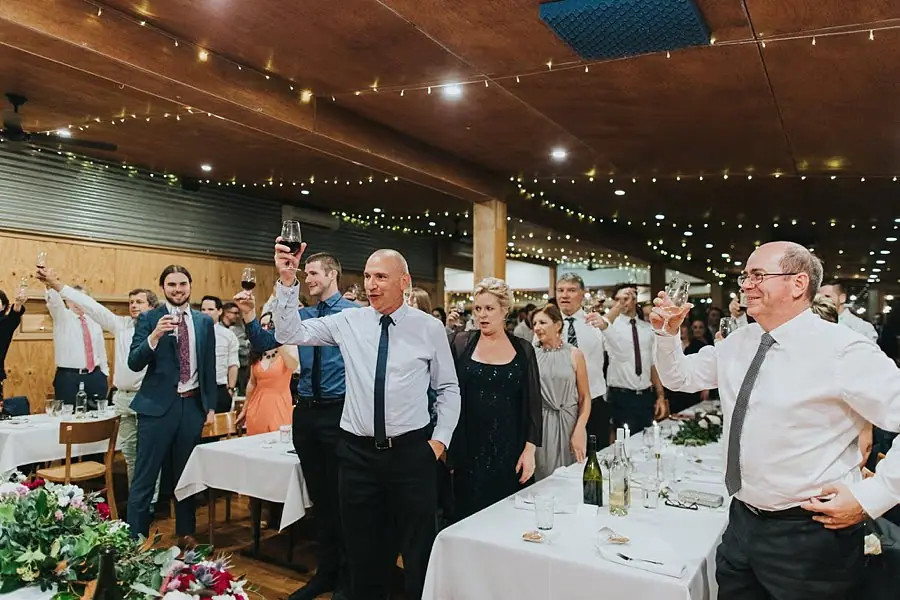 Guests standing and raising glasses beneath the reception lights.